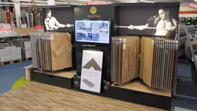 Ausstellung im TTL-Markt Heilbronn mit verschiedenen Dekoren und Mustertafeln des Invictus Vinylbodens. Die Präsentation zeigt Bodenmuster, einen zentralen Bildschirm sowie ergänzende Produktinformationen in einer Verkaufsfläche.